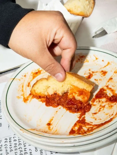 una mano fa la scarpetta con una fetta di pane