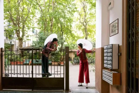 un uomo e una donna sui trampoli con il parasole aperto in un cortile