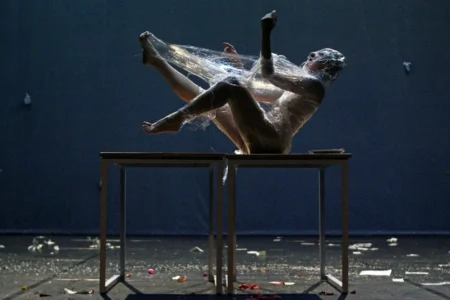 una donna seduta su un tavolo avvolta nel cellophane