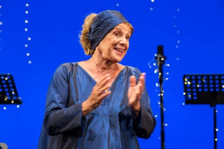 Lella Costa vestita di blu sul palco